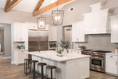 Inspiration for a large transitional u-shaped dark wood floor and brown floor open concept kitchen remodel in San Francisco with a farmhouse sink, shaker cabinets, white cabinets, white backsplash, stainless steel appliances, an island and multicolored countertops