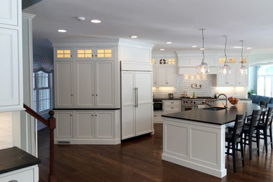 Eat-in kitchen - large transitional l-shaped dark wood floor eat-in kitchen idea in Boston with shaker cabinets, white cabinets, solid surface countertops, white backsplash, stone slab backsplash, paneled appliances and an island