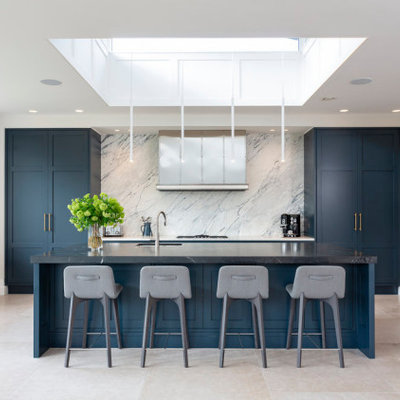 Inspiration for a large contemporary galley porcelain tile and beige floor kitchen remodel in Dublin with an undermount sink, shaker cabinets, blue cabinets, gray backsplash, stainless steel appliances, an island and black countertops