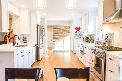 Example of a large trendy light wood floor and beige floor kitchen design in New York with a drop-in sink, shaker cabinets, white cabinets, quartzite countertops, white backsplash, stainless steel appliances, no island and gray countertops