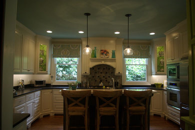 Example of a classic medium tone wood floor kitchen design in Other with a single-bowl sink, raised-panel cabinets, white cabinets, granite countertops, multicolored backsplash, stone tile backsplash, stainless steel appliances and an island