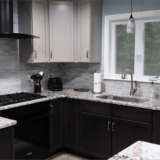 Medium sized traditional u-shaped open plan kitchen in Boston with a submerged sink, shaker cabinets, black cabinets, granite worktops, grey splashback, glass tiled splashback, stainless steel appliances, slate flooring, an island and grey floors.
