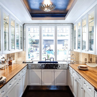 Example of a classic kitchen design in New York with wood countertops, glass-front cabinets, white cabinets and an integrated sink