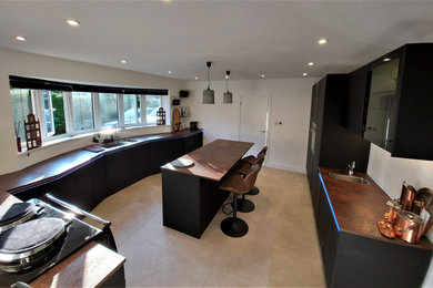 Photo of a large enclosed kitchen in Surrey with flat-panel cabinets, laminate countertops and an island.