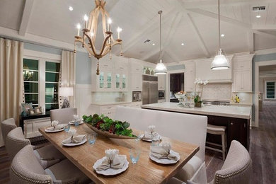 Mid-sized cottage chic medium tone wood floor and gray floor eat-in kitchen photo in Miami with an undermount sink, glass-front cabinets, white cabinets, quartz countertops, white backsplash, porcelain backsplash, stainless steel appliances and an island