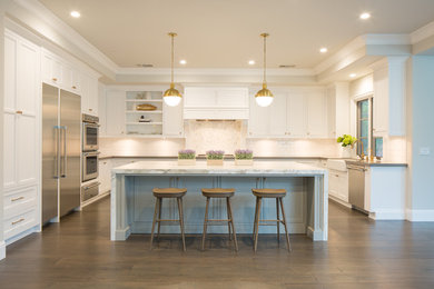 Mid-sized transitional u-shaped medium tone wood floor and beige floor eat-in kitchen photo in Sacramento with a farmhouse sink, shaker cabinets, white cabinets, marble countertops, white backsplash, subway tile backsplash, stainless steel appliances and an island