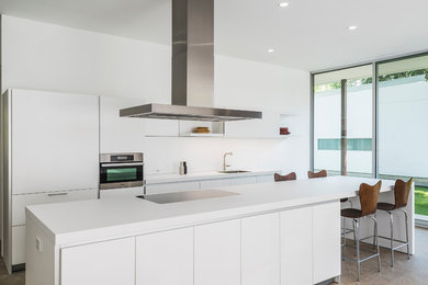 Example of a trendy concrete floor eat-in kitchen design in Dallas with white cabinets, stainless steel appliances and an island