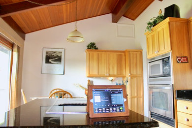 ポートランドにある中くらいなトラディショナルスタイルのおしゃれなアイランドキッチン (シェーカースタイル扉のキャビネット、淡色木目調キャビネット、御影石カウンター、シルバーの調理設備) の写真
