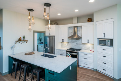 Mid-sized transitional u-shaped medium tone wood floor and brown floor eat-in kitchen photo in Other with an undermount sink, shaker cabinets, white cabinets, quartz countertops, white backsplash, ceramic backsplash, stainless steel appliances, an island and white countertops