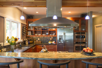Foto på ett mellanstort funkis kök, med en undermonterad diskho, skåp i shakerstil, bruna skåp, granitbänkskiva, stänkskydd i glaskakel, rostfria vitvaror och en köksö
