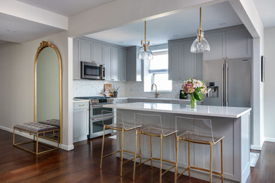 Example of a transitional l-shaped dark wood floor and brown floor eat-in kitchen design in New York with an undermount sink, shaker cabinets, gray cabinets, quartz countertops, white backsplash, marble backsplash, stainless steel appliances, an island and white countertops