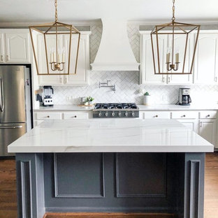 This is an example of a large country single-wall kitchen in Raleigh with raised-panel cabinets, white cabinets, marble benchtops, white splashback, subway tile splashback, stainless steel appliances, medium hardwood floors, with island, brown floor and white benchtop.