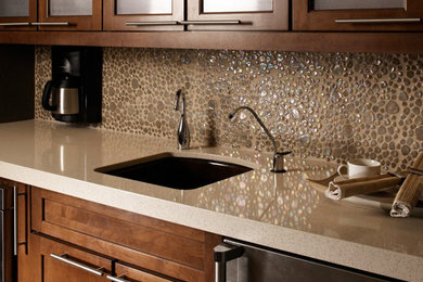 Example of a mid-sized classic l-shaped kitchen design in New York with an undermount sink, shaker cabinets, medium tone wood cabinets, quartz countertops, beige backsplash, stone tile backsplash and stainless steel appliances