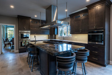 Große Küche mit dunklen Holzschränken, Granit-Arbeitsplatte, Küchenrückwand in Weiß, Küchengeräten aus Edelstahl, Kücheninsel, grauem Boden und brauner Arbeitsplatte in Philadelphia