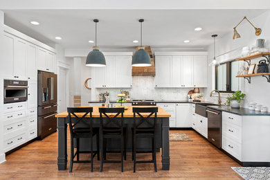 Inspiration for a transitional u-shaped medium tone wood floor kitchen remodel in Other with a farmhouse sink, shaker cabinets, white cabinets, wood countertops, multicolored backsplash, stainless steel appliances and an island
