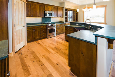 Bild på ett mellanstort amerikanskt l-kök, med en rustik diskho, luckor med infälld panel, skåp i mellenmörkt trä, granitbänkskiva, ljust trägolv och en köksö