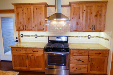 Bild på ett mellanstort amerikanskt linjärt skafferi, med skåp i shakerstil, skåp i ljust trä, granitbänkskiva, stänkskydd i keramik, rostfria vitvaror, mellanmörkt trägolv och en köksö