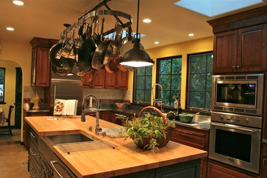 Immagine di una cucina abitabile classica con lavello sottopiano, ante con bugna sagomata, ante grigie, top in acciaio inossidabile, paraspruzzi beige e elettrodomestici in acciaio inossidabile