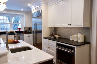 ミネアポリスにある広いトランジショナルスタイルのおしゃれなキッチン (アンダーカウンターシンク、落し込みパネル扉のキャビネット、白いキャビネット、クオーツストーンカウンター、茶色いキッチンパネル、ガラスタイルのキッチンパネル、シルバーの調理設備、無垢フローリング、茶色い床、白いキッチンカウンター) の写真