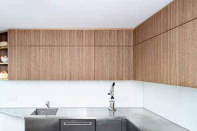 Minimalist eat-in kitchen photo in Amsterdam with dark wood cabinets, stainless steel countertops and white backsplash