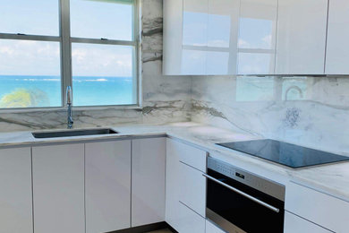 Mid-sized minimalist l-shaped marble floor and beige floor enclosed kitchen photo in Other with a drop-in sink, flat-panel cabinets, white cabinets, marble countertops, multicolored backsplash, marble backsplash, white appliances, no island and multicolored countertops