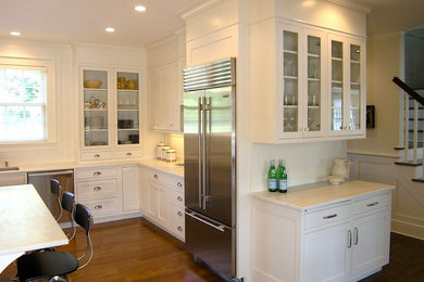 Modelo de cocina de estilo de casa de campo con fregadero bajoencimera, armarios con paneles empotrados, encimera de mármol, salpicadero blanco y electrodomésticos de acero inoxidable