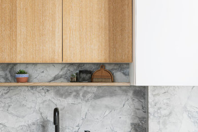 Inspiration for a medium sized scandinavian single-wall open plan kitchen in Sussex with a submerged sink, flat-panel cabinets, white cabinets, marble worktops, grey splashback, marble splashback, integrated appliances, light hardwood flooring, an island, brown floors, grey worktops and a coffered ceiling.