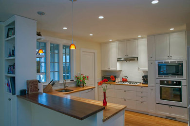 Eat-in kitchen - mid-sized contemporary l-shaped light wood floor eat-in kitchen idea in Boston with a single-bowl sink, white cabinets, wood countertops, white backsplash and subway tile backsplash