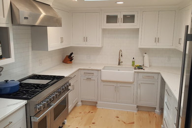 ボストンにある中くらいなトランジショナルスタイルのおしゃれなコの字型キッチン (エプロンフロントシンク、インセット扉のキャビネット、白いキャビネット、白いキッチンパネル、セラミックタイルのキッチンパネル、淡色無垢フローリング) の写真