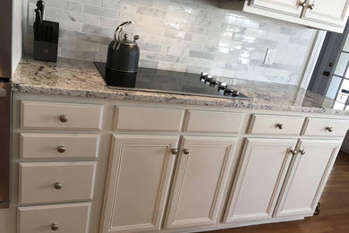 Example of a mid-sized classic medium tone wood floor kitchen design in Atlanta with recessed-panel cabinets, white cabinets, granite countertops, white backsplash, marble backsplash and stainless steel appliances