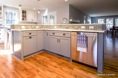 Example of a classic medium tone wood floor kitchen design in Raleigh with shaker cabinets, yellow cabinets, white backsplash, stainless steel appliances and an island