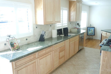 Photo of a medium sized traditional galley enclosed kitchen in San Diego with a double-bowl sink, beaded cabinets, light wood cabinets, beige splashback, ceramic splashback, stainless steel appliances, ceramic flooring and no island.