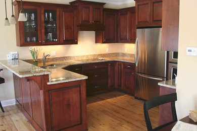 Eat-in kitchen - u-shaped light wood floor eat-in kitchen idea in Milwaukee with a double-bowl sink, raised-panel cabinets, dark wood cabinets, granite countertops and stainless steel appliances