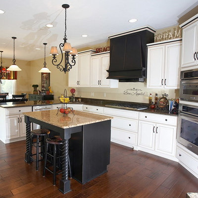Mid-sized eclectic l-shaped dark wood floor eat-in kitchen photo in Indianapolis with a single-bowl sink, raised-panel cabinets, white cabinets, granite countertops, stainless steel appliances, an island and beige backsplash