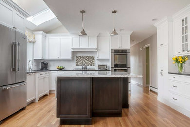 Example of a mid-sized transitional l-shaped light wood floor kitchen design in Chicago with an undermount sink, shaker cabinets, white cabinets, granite countertops, white backsplash, subway tile backsplash, stainless steel appliances and an island