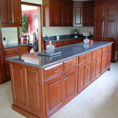 Transitional marble floor enclosed kitchen photo in Other with raised-panel cabinets, medium tone wood cabinets, granite countertops, beige backsplash, subway tile backsplash, stainless steel appliances and an island