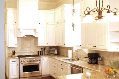 Elegant kitchen photo in New Orleans with stainless steel appliances and travertine backsplash