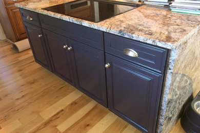 Example of a mid-sized classic light wood floor kitchen design in St Louis with raised-panel cabinets, black cabinets, granite countertops and an island