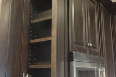 ヒューストンにある中くらいなトラディショナルスタイルのおしゃれなII型キッチン (アンダーカウンターシンク、レイズドパネル扉のキャビネット、濃色木目調キャビネット、御影石カウンター、シルバーの調理設備) の写真