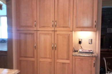 Diseño de cocina lineal grande con despensa y puertas de armario de madera oscura