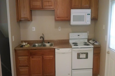 コロンバスにあるトラディショナルスタイルのおしゃれなキッチン (ダブルシンク、中間色木目調キャビネット、白い調理設備、アイランドなし) の写真