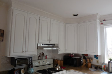Eat-in kitchen - large traditional u-shaped eat-in kitchen idea in New York with raised-panel cabinets, white cabinets, granite countertops, white backsplash, ceramic backsplash, white appliances and a peninsula