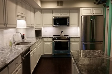 Inspiration for a large timeless u-shaped dark wood floor kitchen pantry remodel in Philadelphia with an undermount sink, raised-panel cabinets, white cabinets, granite countertops, white backsplash, ceramic backsplash, stainless steel appliances and an island