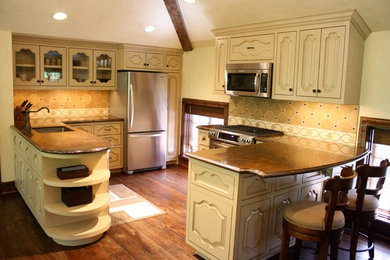 Example of a mid-sized arts and crafts galley medium tone wood floor and brown floor eat-in kitchen design in Houston with a single-bowl sink, raised-panel cabinets, white cabinets, granite countertops, beige backsplash, porcelain backsplash, stainless steel appliances and no island