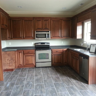 Mid-sized traditional u-shaped eat-in kitchen in Other with a double-bowl sink, raised-panel cabinets, stainless steel cabinets, quartz benchtops, stainless steel appliances, porcelain floors, no island, grey floor and grey benchtop.