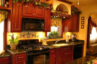 Foto på ett stort linjärt kök och matrum, med en dubbel diskho, skåp i mörkt trä, granitbänkskiva, svarta vitvaror och en köksö