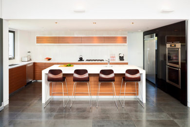 Eat-in kitchen - large contemporary u-shaped cement tile floor and gray floor eat-in kitchen idea in Vancouver with an undermount sink, flat-panel cabinets, medium tone wood cabinets, quartz countertops, white backsplash, stone slab backsplash, stainless steel appliances, an island and white countertops