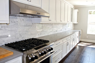 Idee per una grande cucina minimal con paraspruzzi bianco, paraspruzzi in marmo, elettrodomestici in acciaio inossidabile, parquet scuro e pavimento marrone