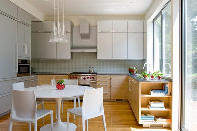 Moderne Küche mit Küchenrückwand in Blau, Betonarbeitsplatte, hellen Holzschränken, Rückwand aus Glasfliesen, Küchengeräten aus Edelstahl, Unterbauwaschbecken und braunem Holzboden in Boston