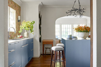 Medium sized mediterranean open plan kitchen in Dallas with a submerged sink, flat-panel cabinets, grey cabinets, engineered stone countertops, multi-coloured splashback, terracotta splashback, integrated appliances, medium hardwood flooring, an island, brown floors and beige worktops.